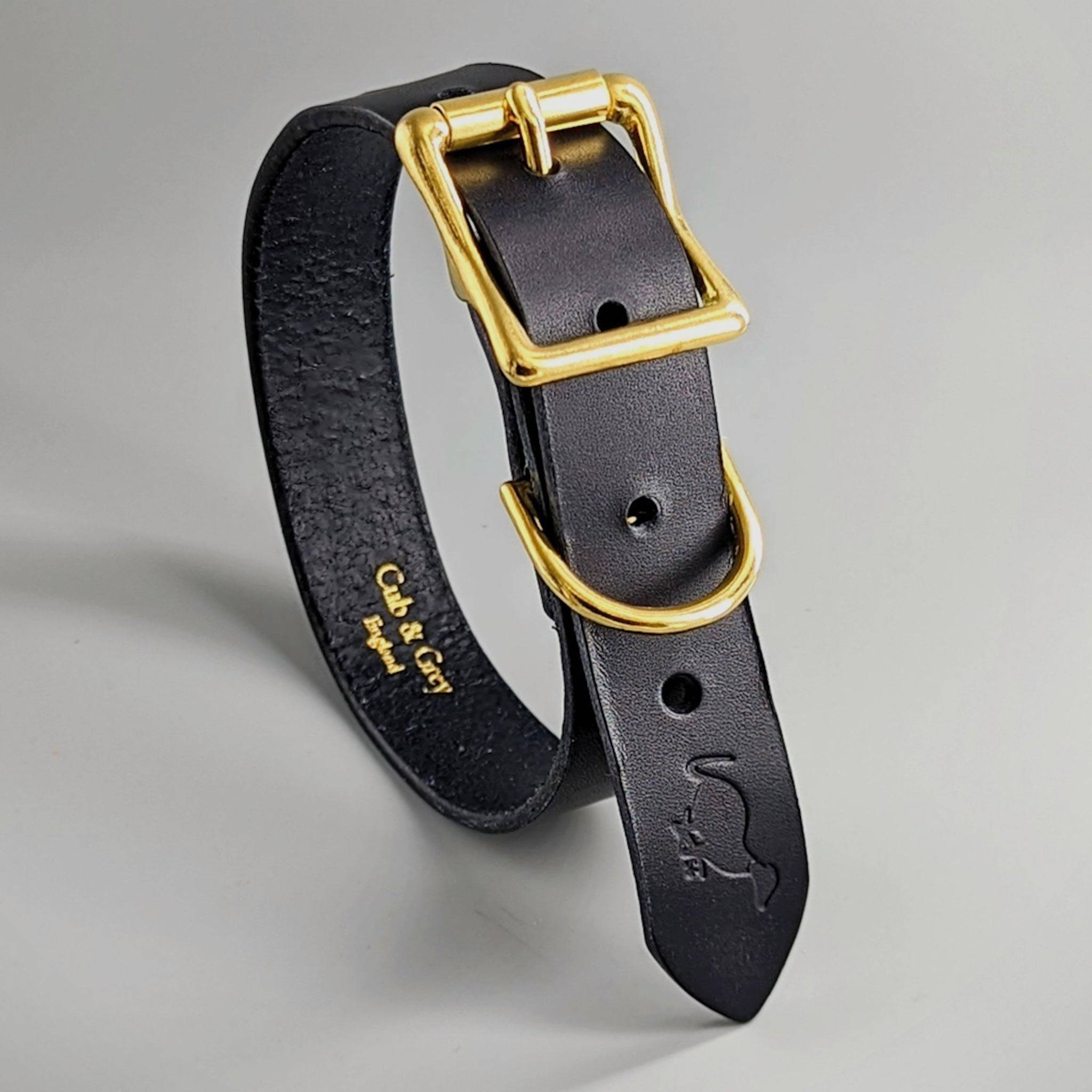 Black luxury British leather dog collar with gold hardware and embossed personalization text inside