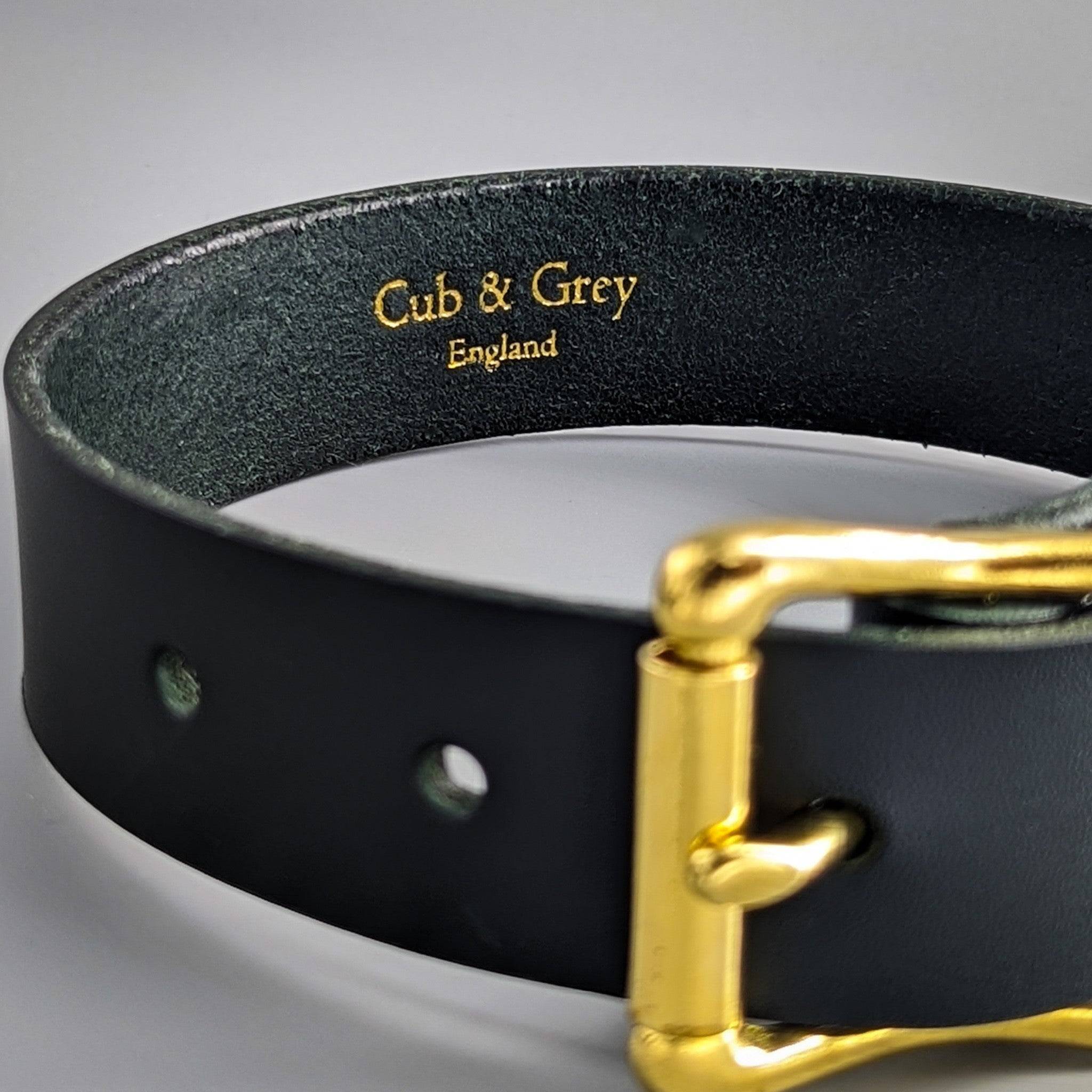 Black luxury leather dog collar detail showing personalised gold-embossed branding and premium brass hardware