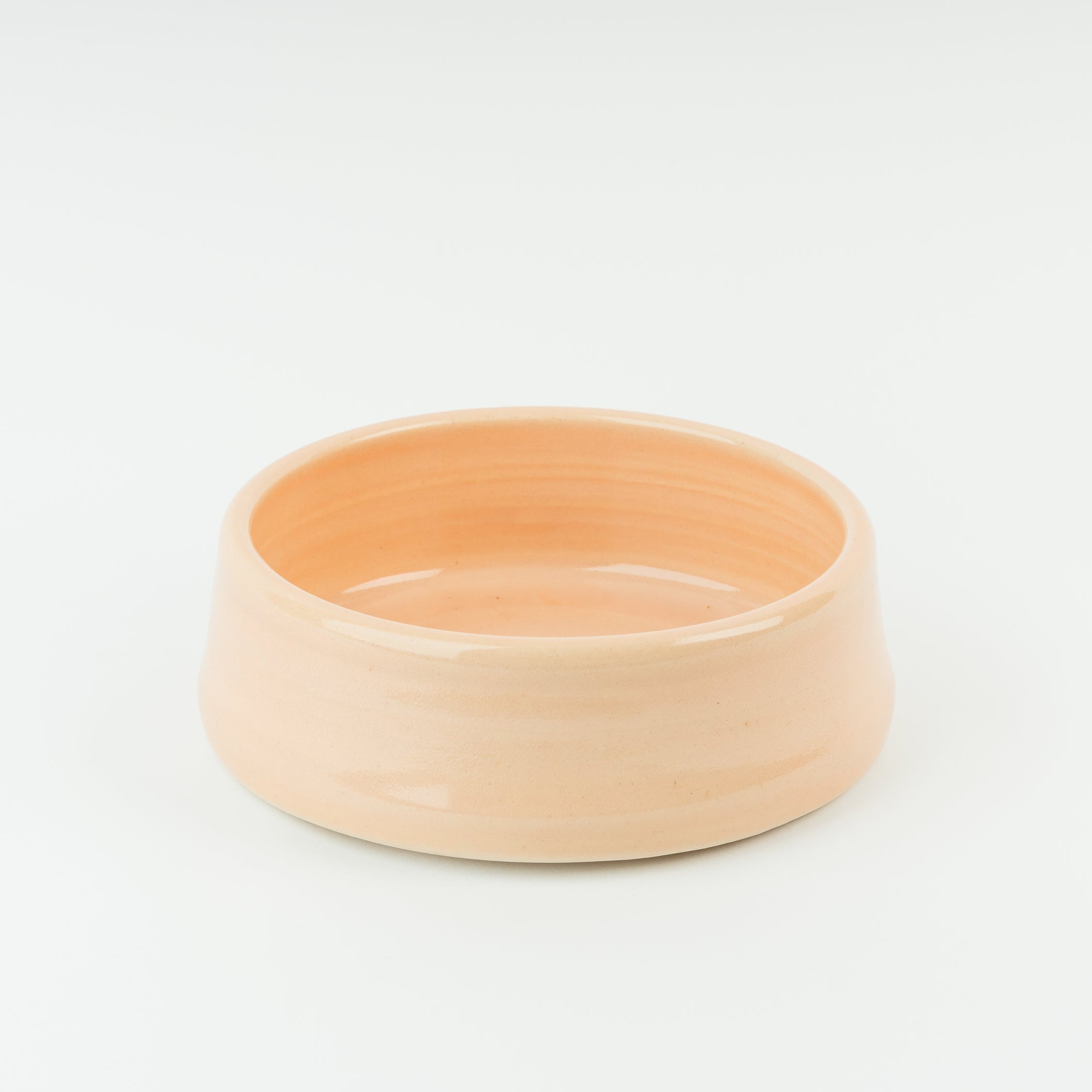 Handmade British stoneware dog bowl in warm peach glaze, showing artisan pottery craftsmanship from Derbyshire