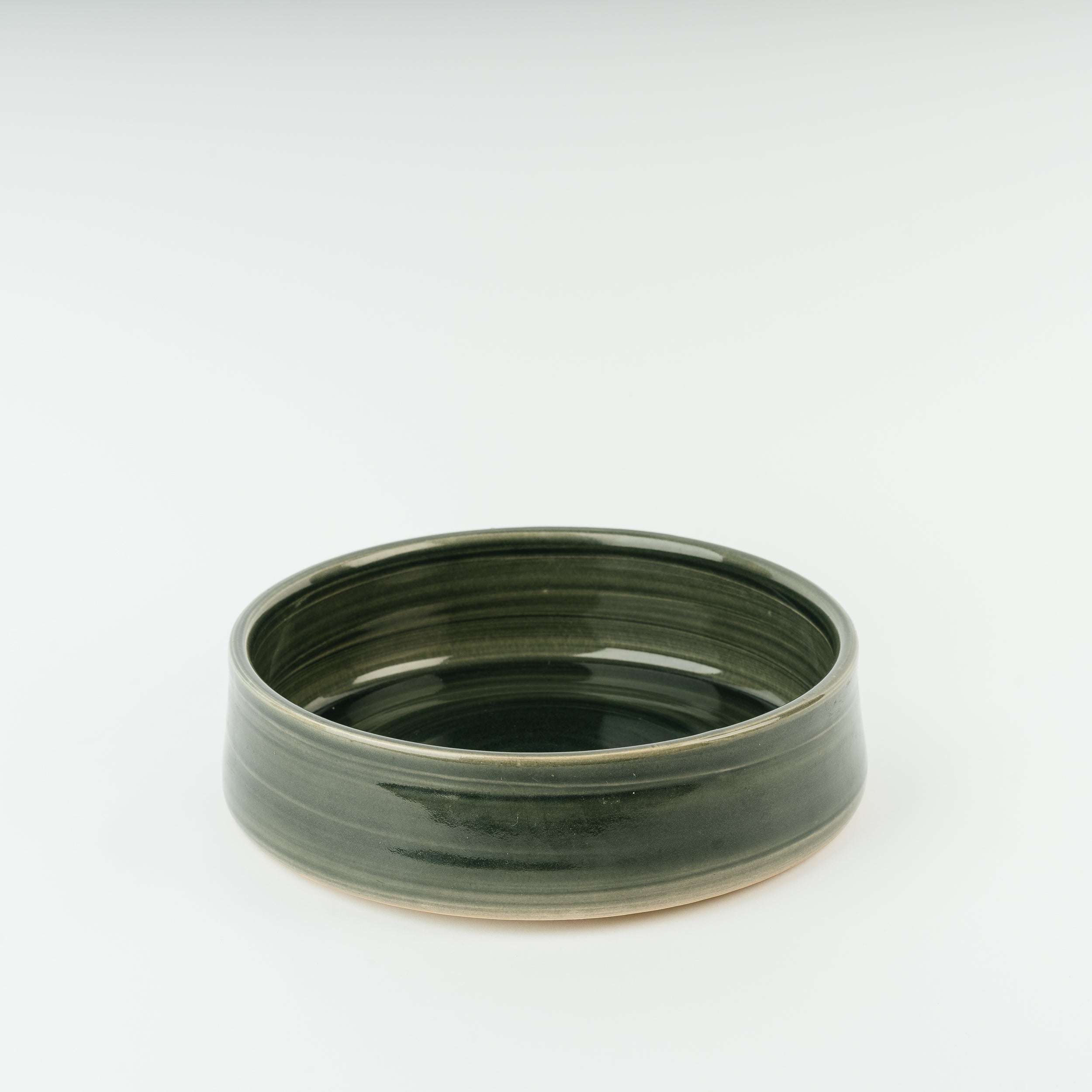 Handmade British ceramic dog bowl in forest green stoneware with visible pottery rings, crafted by Derbyshire artisans