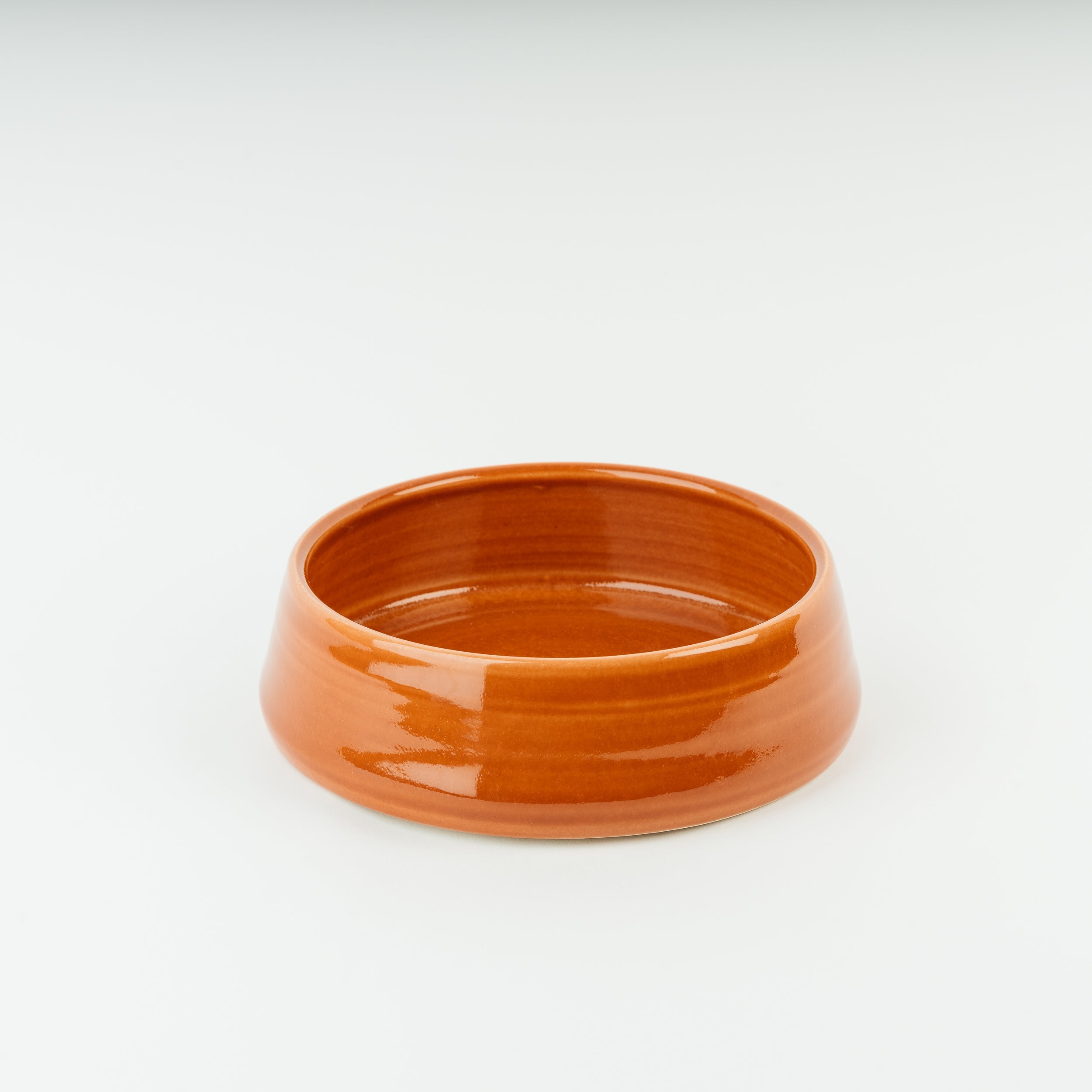 Handmade ceramic dog bowl in warm terracotta glaze, British stoneware pottery with traditional craftsmanship finish