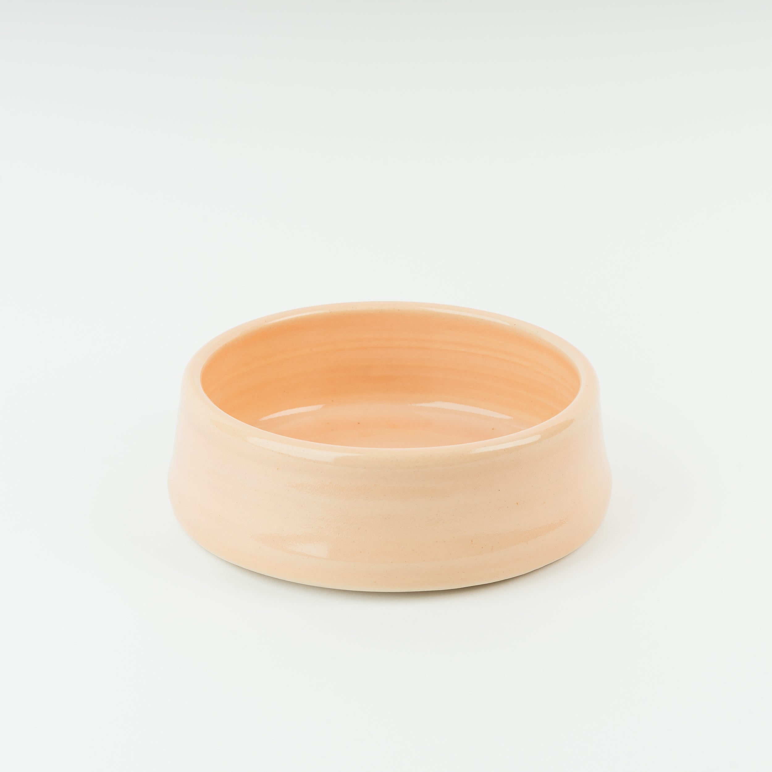Handmade stoneware dog bowl in warm peach glaze, showcasing traditional British pottery craftsmanship