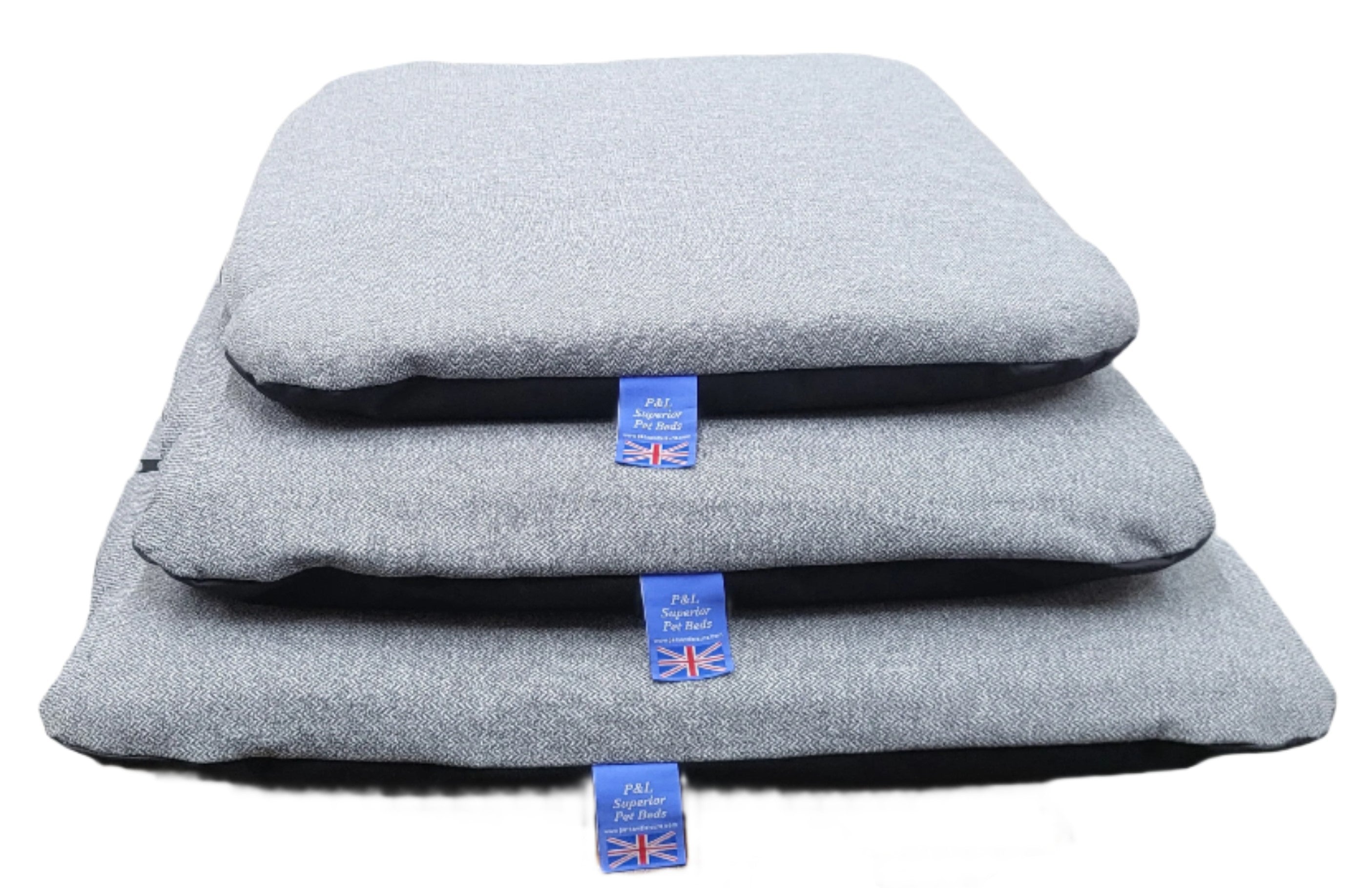 Grey Orkney tweed dog beds stacked in three sizes with blue Union Jack P&L Superior Pet Beds labels showing British craftsmanship