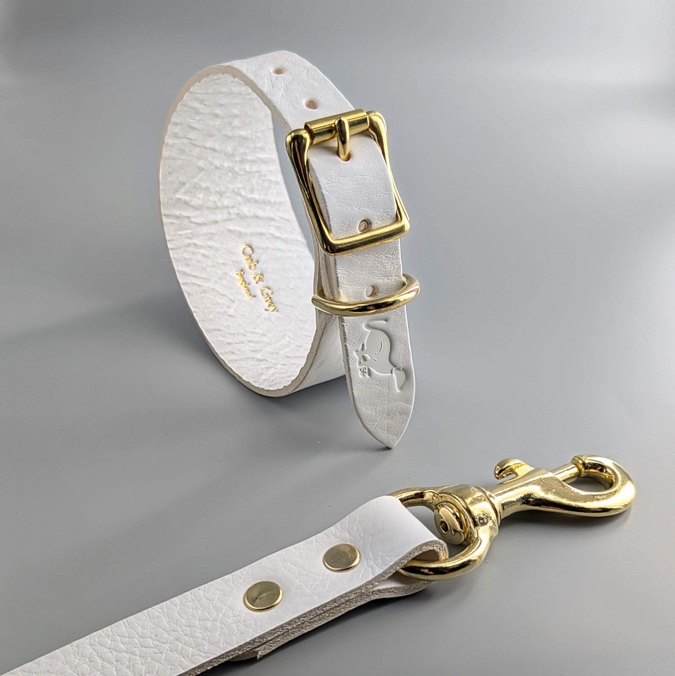 White leather luxury whippet collar and matching lead with gold rivets and brass buckle on gray background