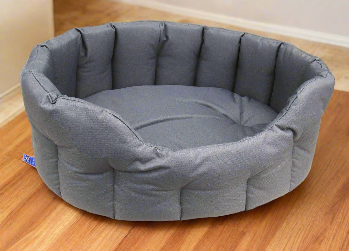 Grey waterproof oval dog bed with high padded sides and tufted cushion on wooden floor - heavy duty design