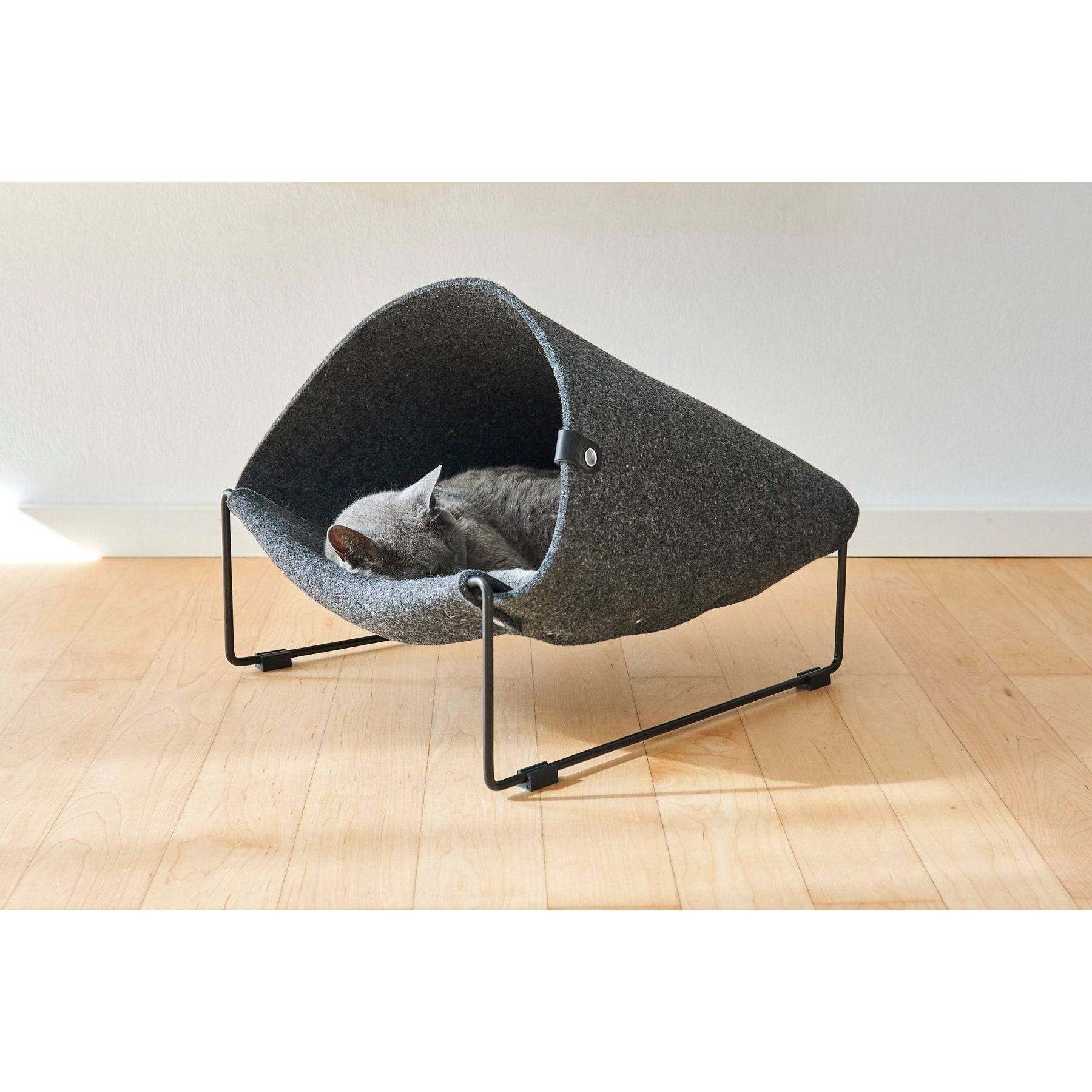 Grey cat sleeping in MiaCara Loggia designer cat cave with minimalist black metal frame on wooden floor