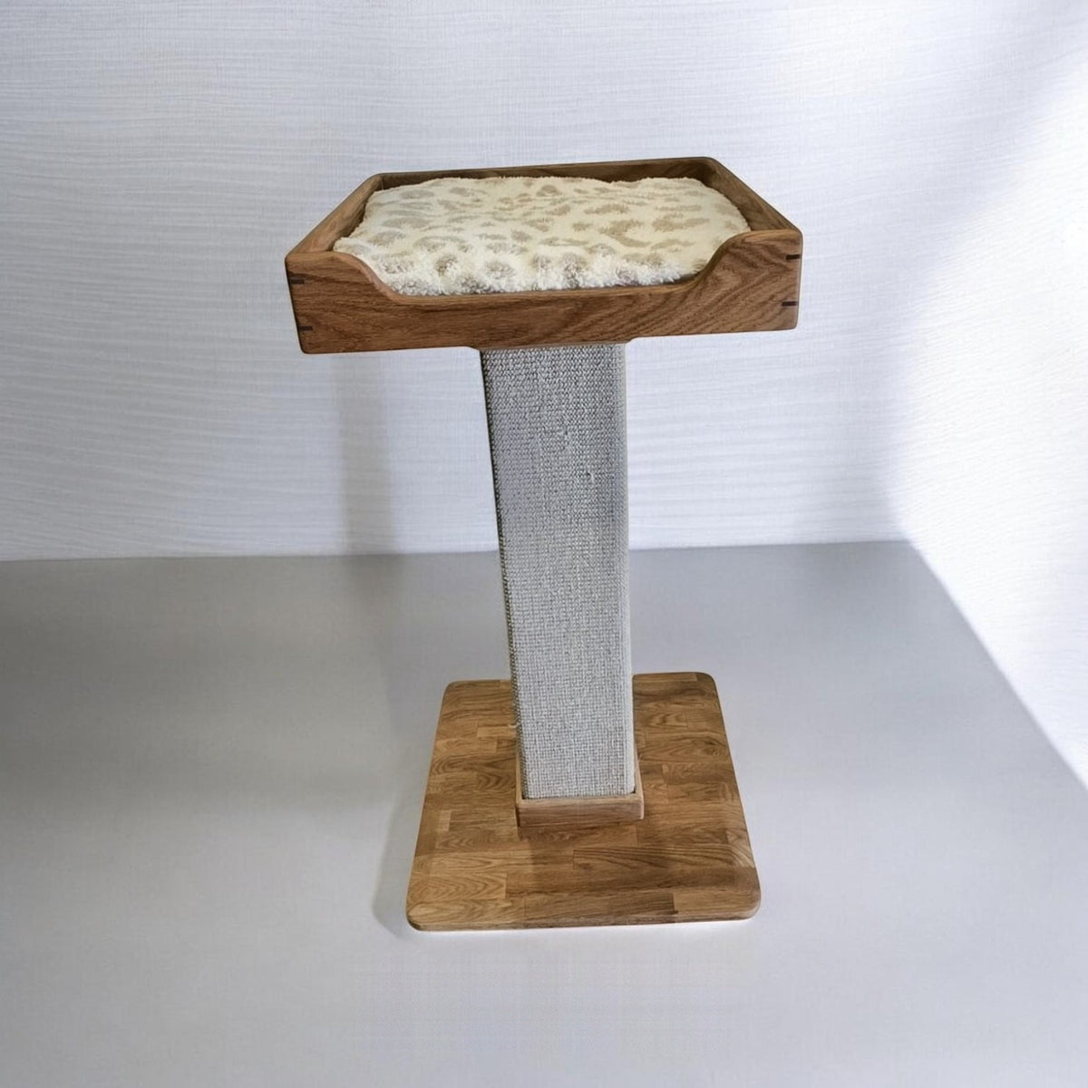 Handmade cat tree with one bed with a patterned cushion, a sisal carpet post and a solid oak base, front view