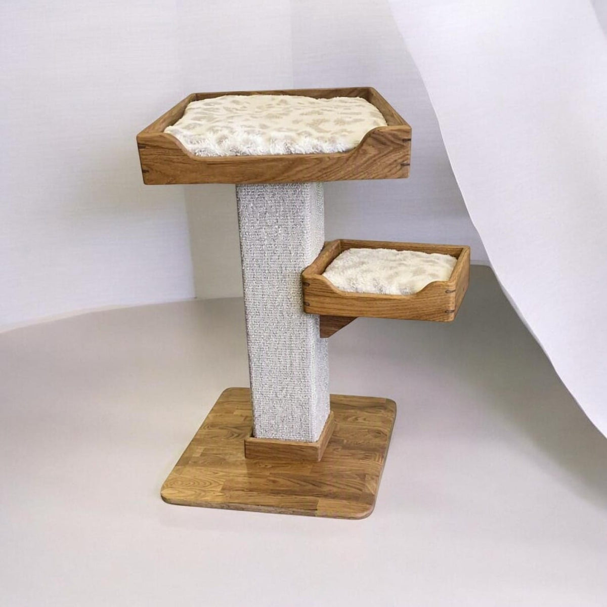 Handmade two-bed cat tree with cream cushions, sisal carpet post and solid oak base, three-quarter view