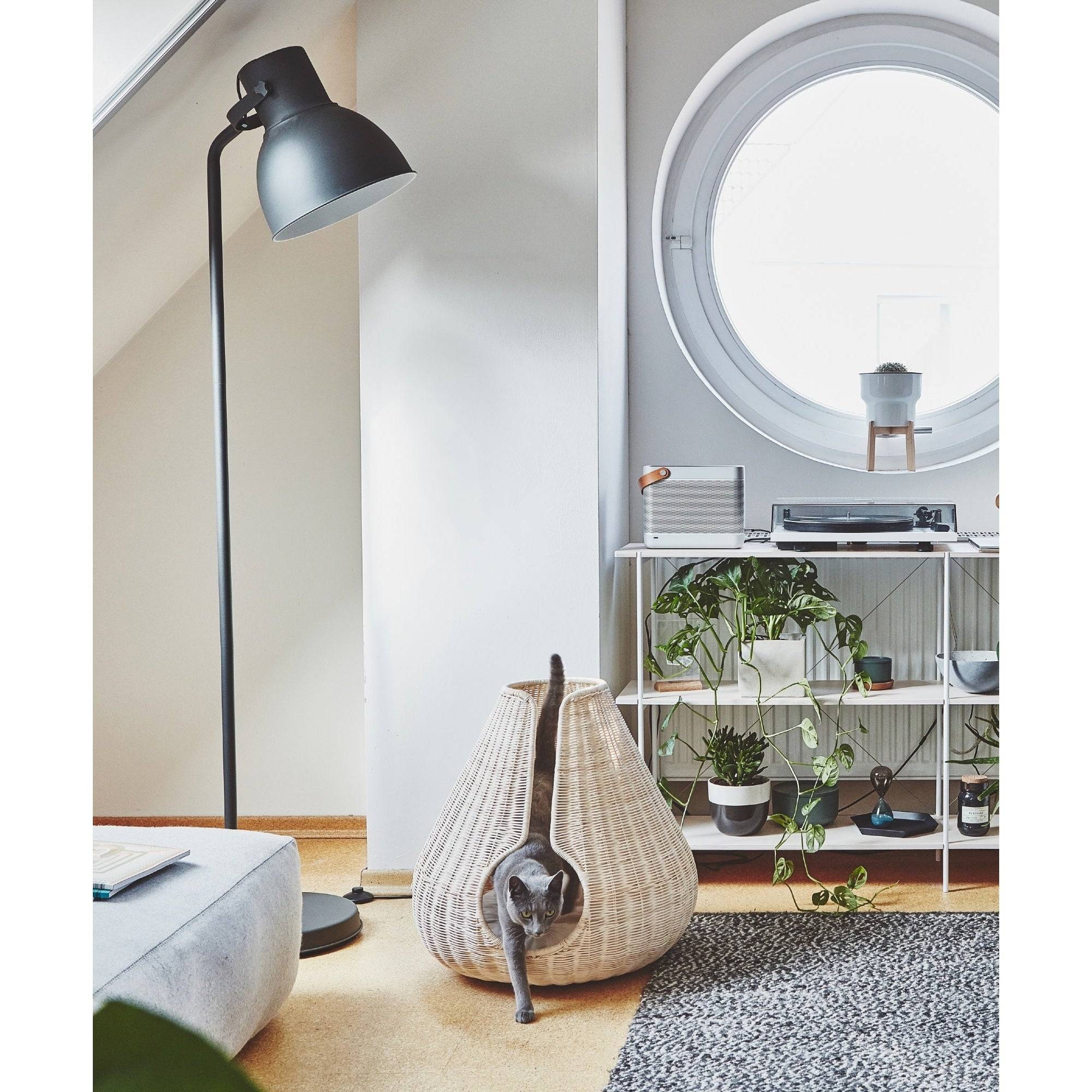 MiaCara Perla woven cat cave in natural rattan with grey cat inside, styled in modern minimalist living room