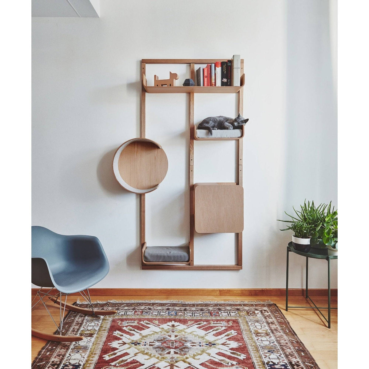 A wall-mounted MiaCara Alto cat climbing system in solid oak with shelves, a round nest and a scratching panel in a modern living room