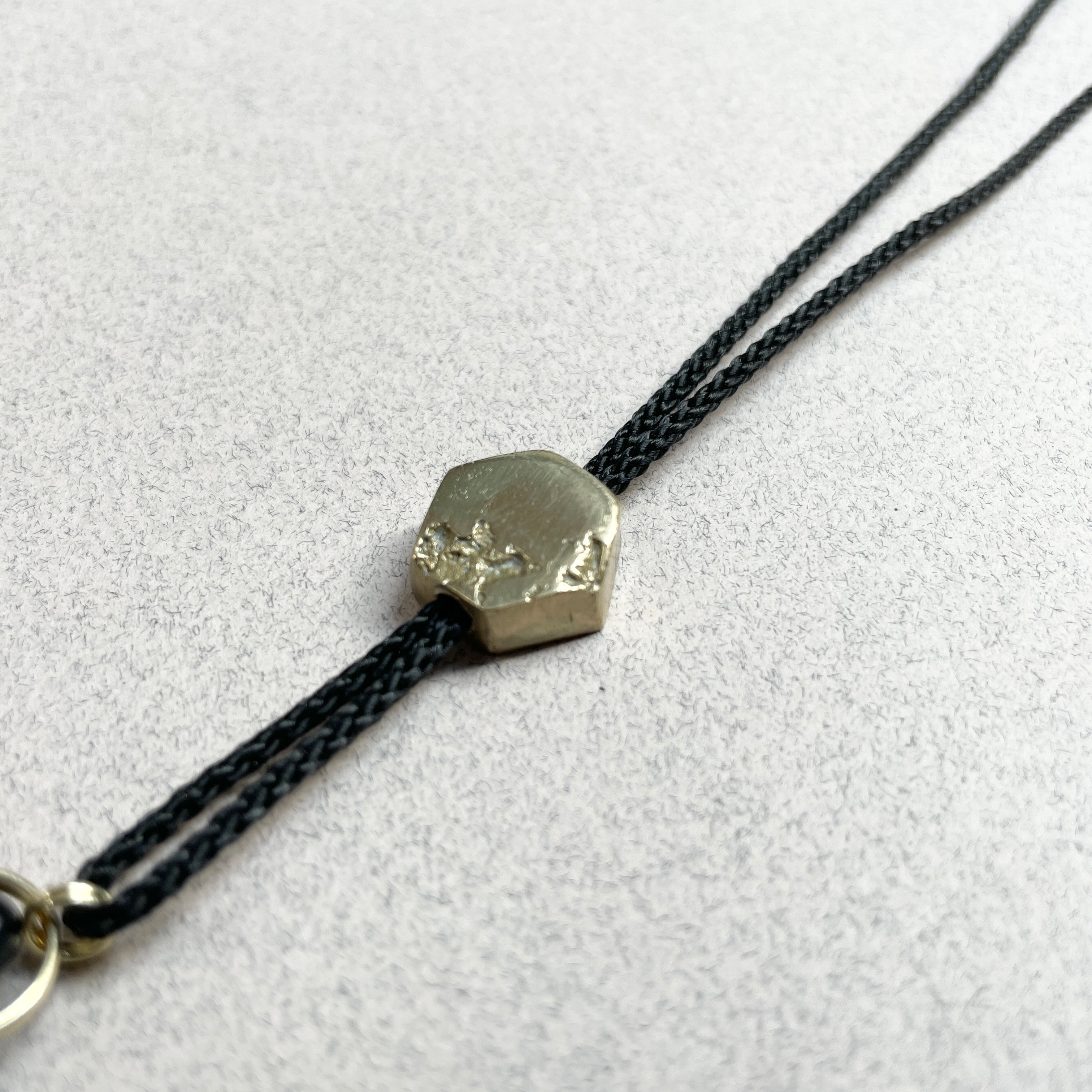 Close-up of Oonalfie Black and Gold lanyard showing classic black whipping and brass clip detail
