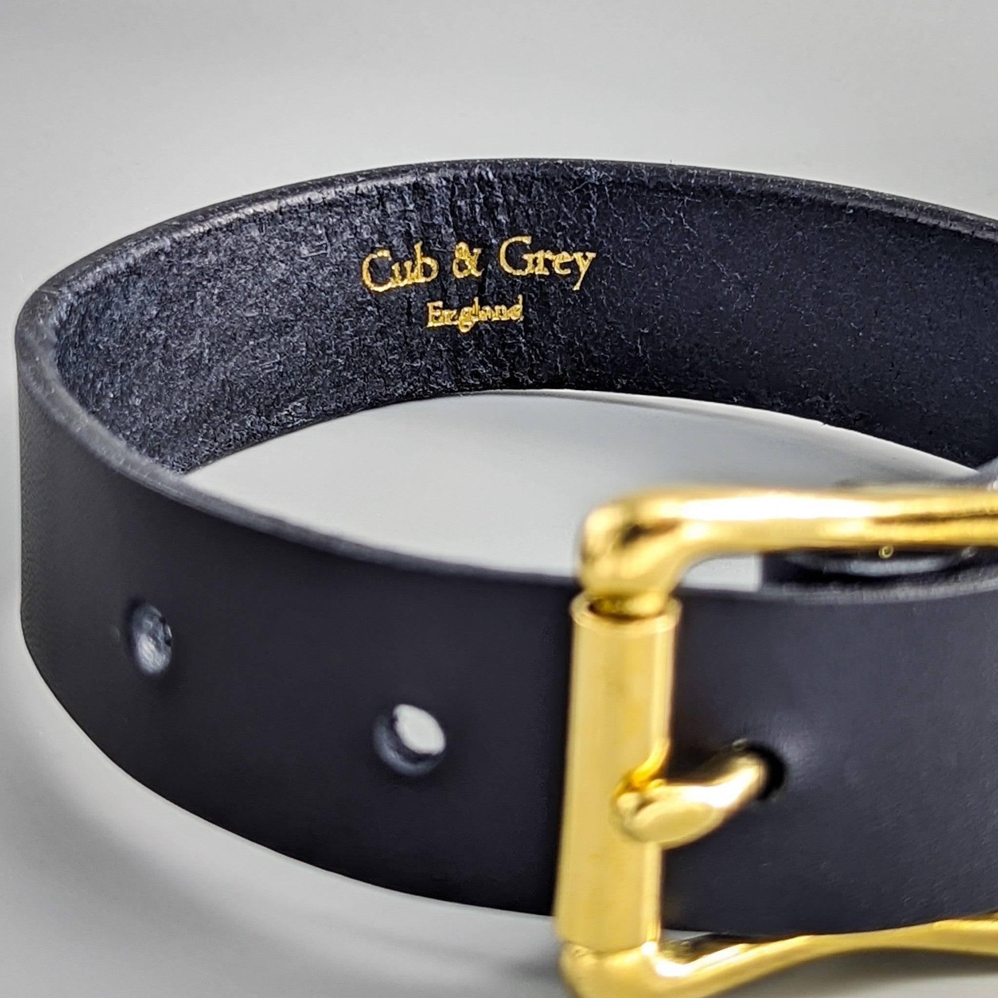 Black personalised leather dog collar close-up with gold-embossed 'Cub & Grey England' branding and brass buckle