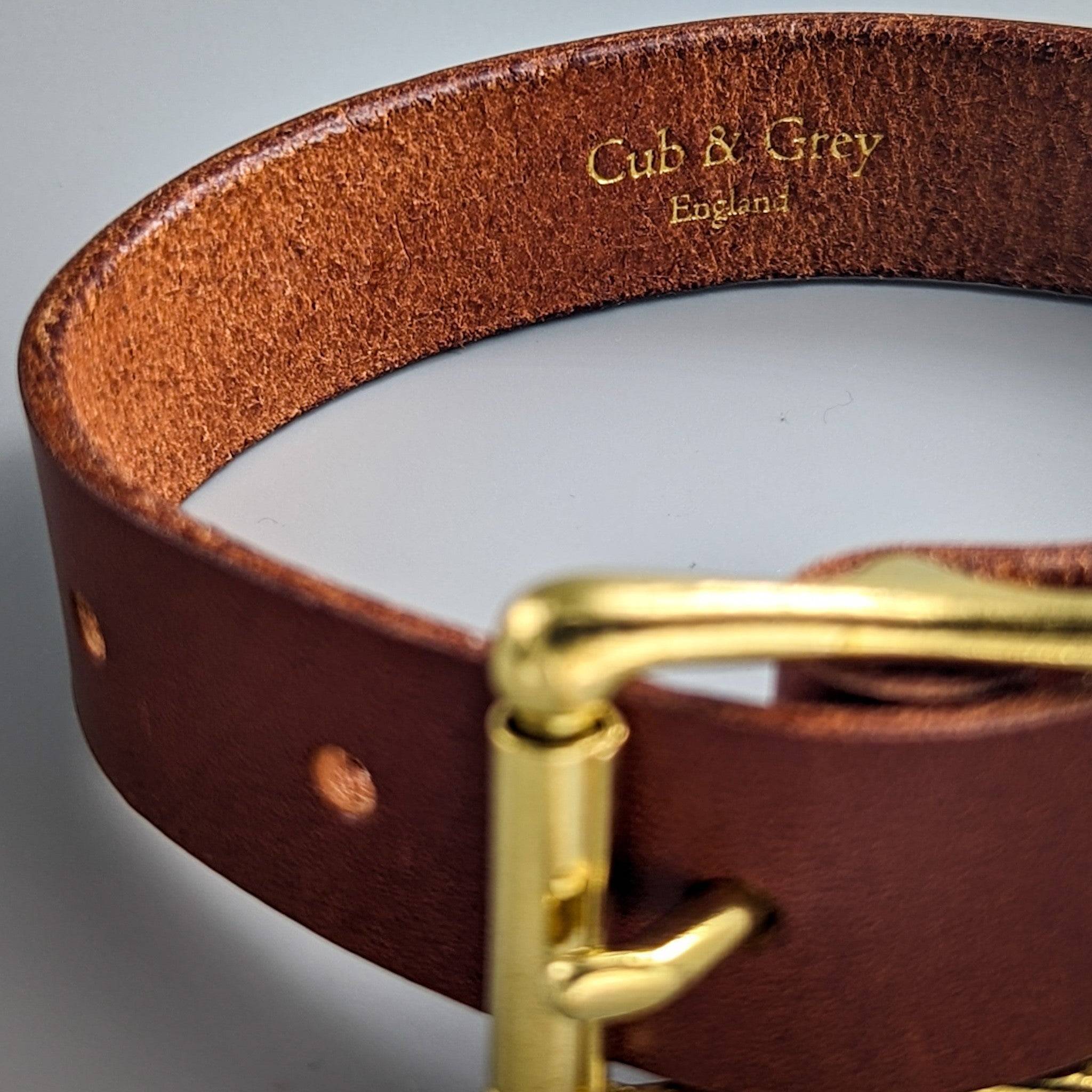 Brown leather dog collar close-up featuring gold-embossed personalised branding and quality stitched construction