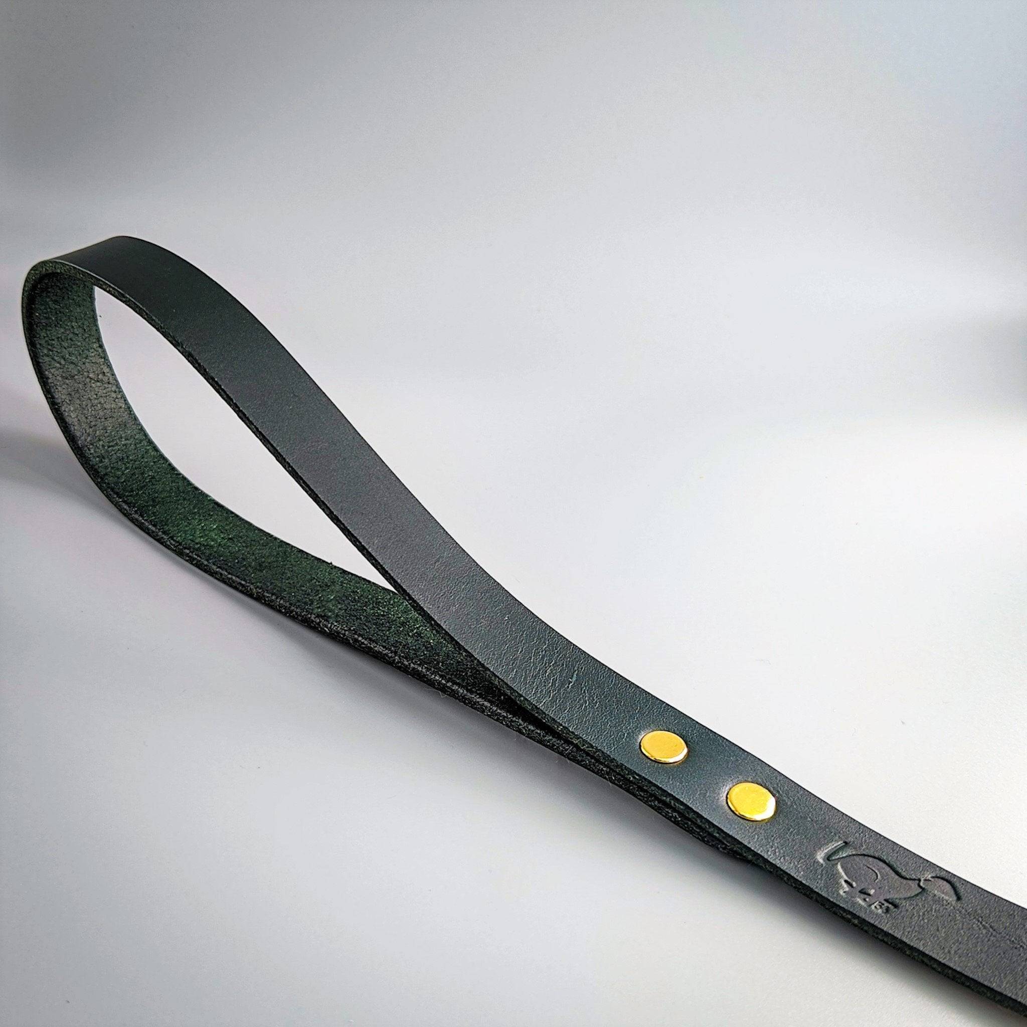 Dark green leather Cerberus dog lead with brass rivets and embossed logo showing rich textured finish