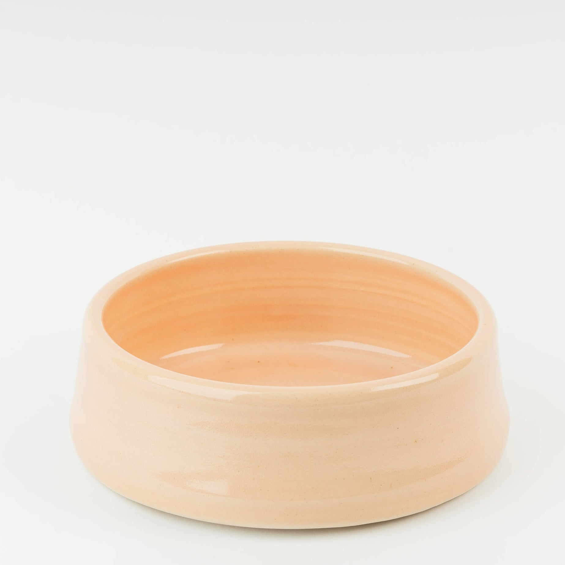 Handmade peach ceramic dog bowl in glossy Derbyshire stoneware showing artisan craftsmanship and traditional pottery