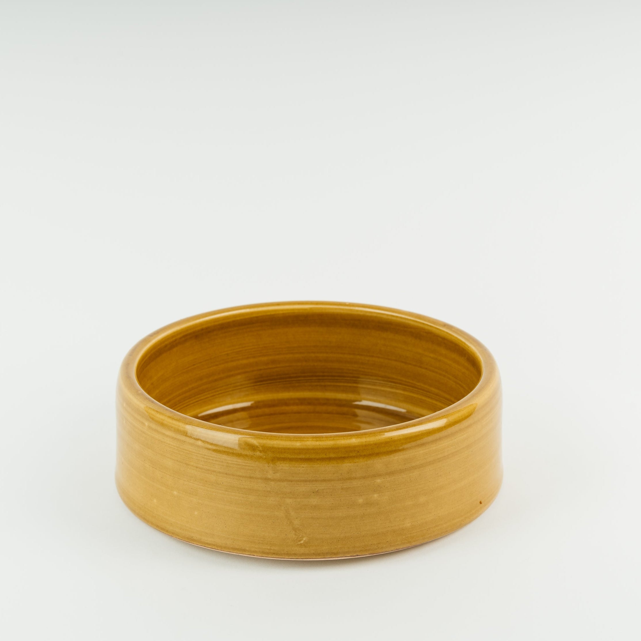 Handmade ceramic dog bowl in golden glaze showing traditional British pottery craftsmanship and stoneware construction