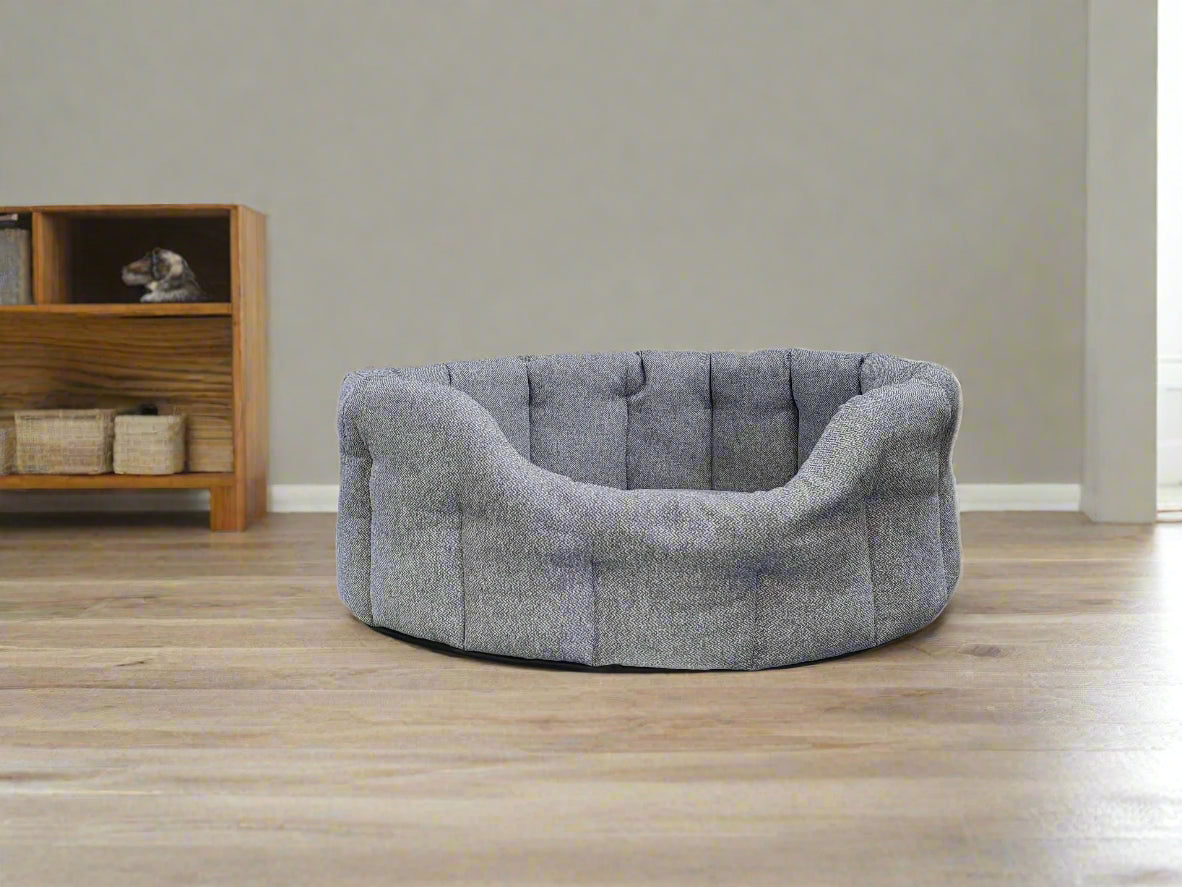 Grey Orkney tweed oval dog bed with tufted cushioning on wooden floor in modern home interior setting