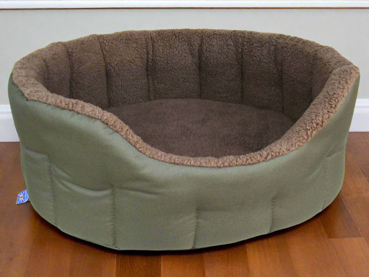 Olive green waterproof oval dog bed with brown fleece lining and quilted bolster sides on wooden floor