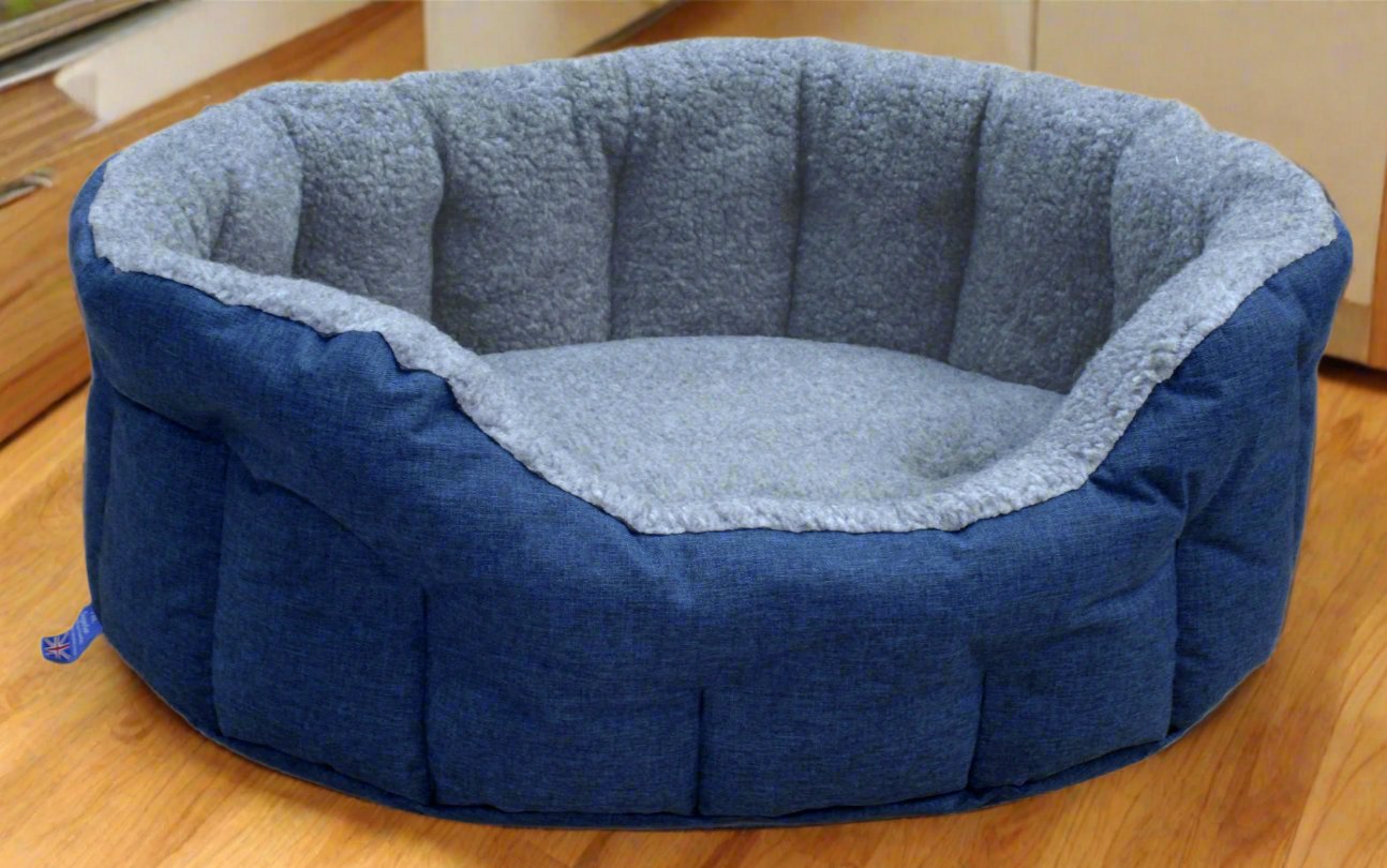 Blue fleece lined oval dog bed with grey interior padding and quilted sides on wooden floor - waterproof UK made pet bed