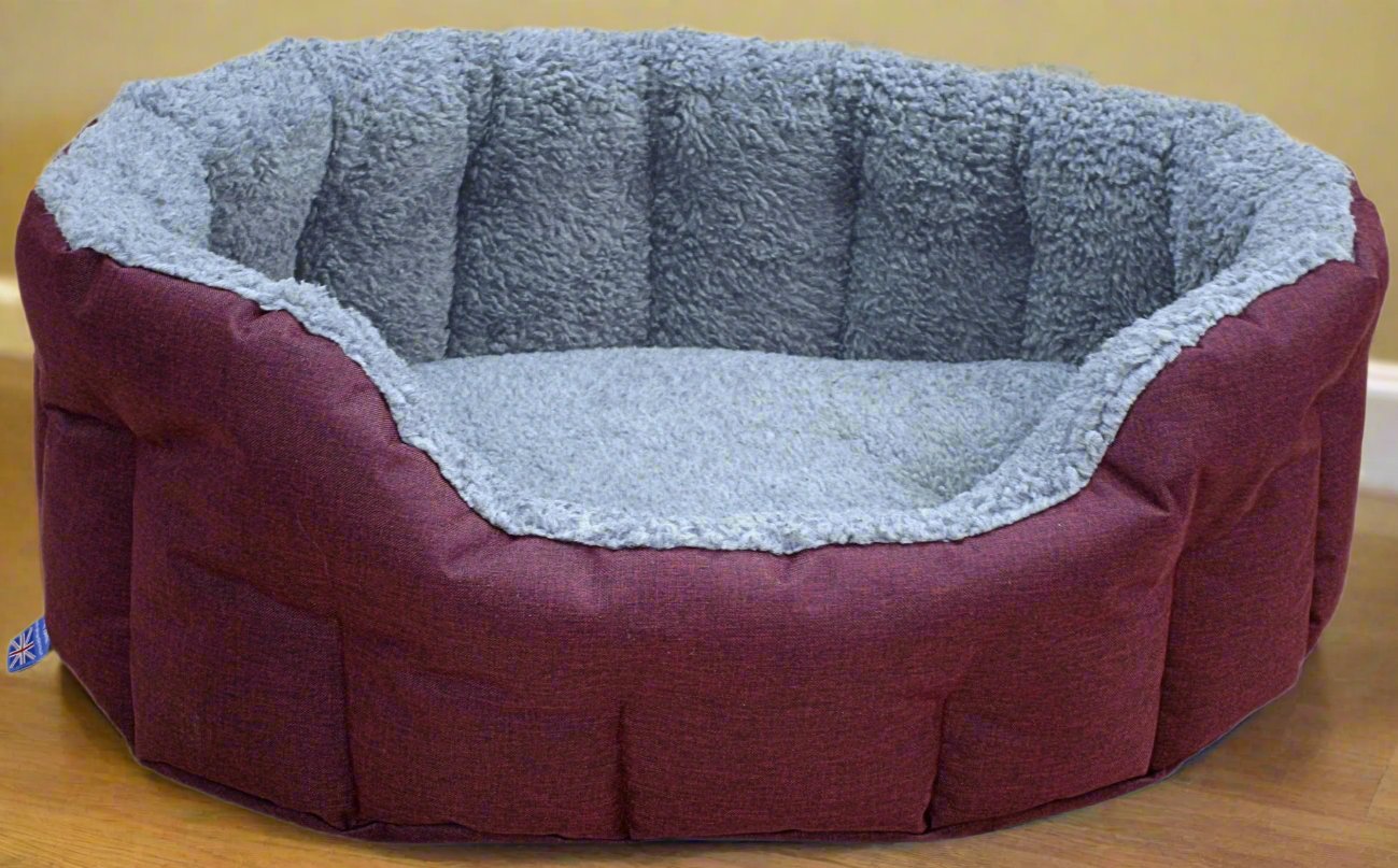 Burgundy oval dog bed with grey fleece lining and bolster sides, British-made waterproof washable pet bedding