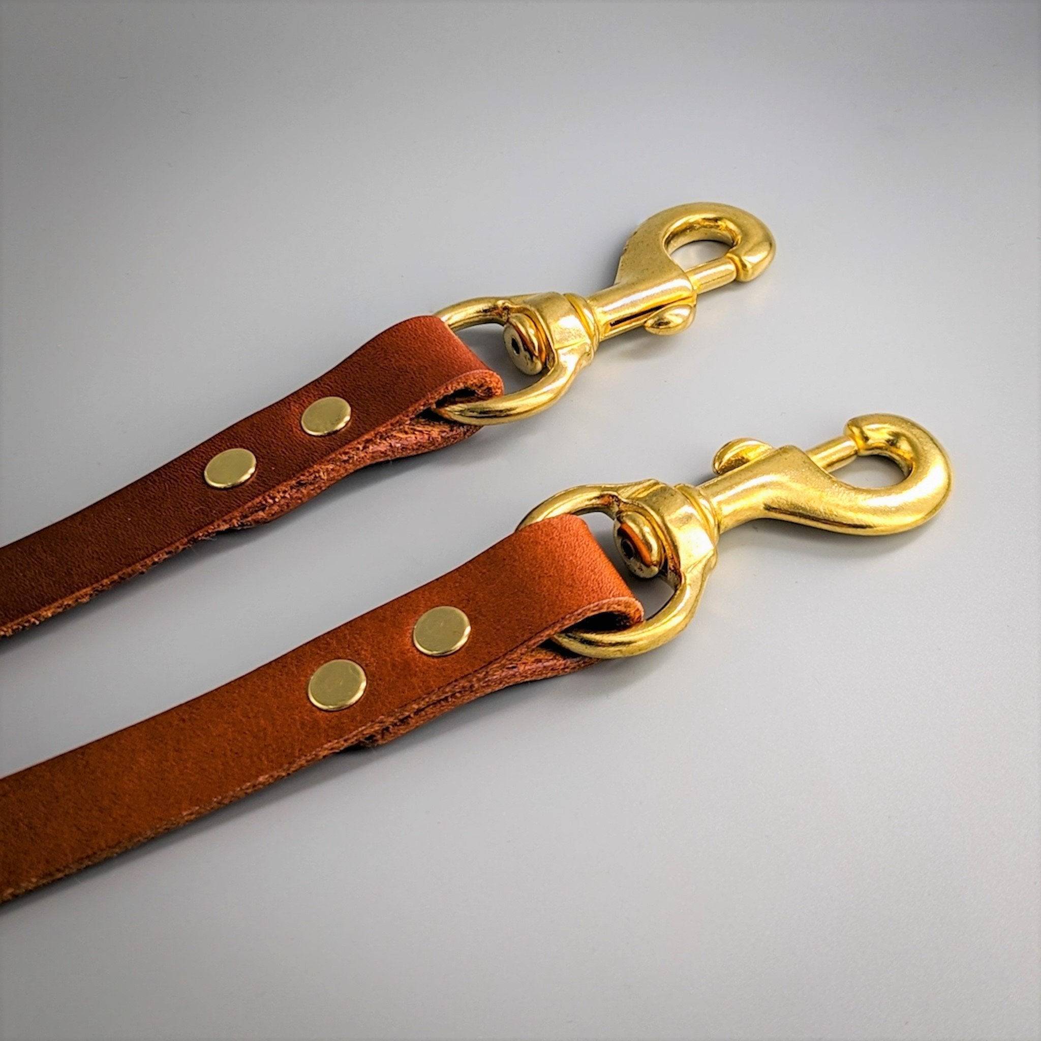 Two brown leather training leads with brass swivel clips and rivets displaying adjustable functionality