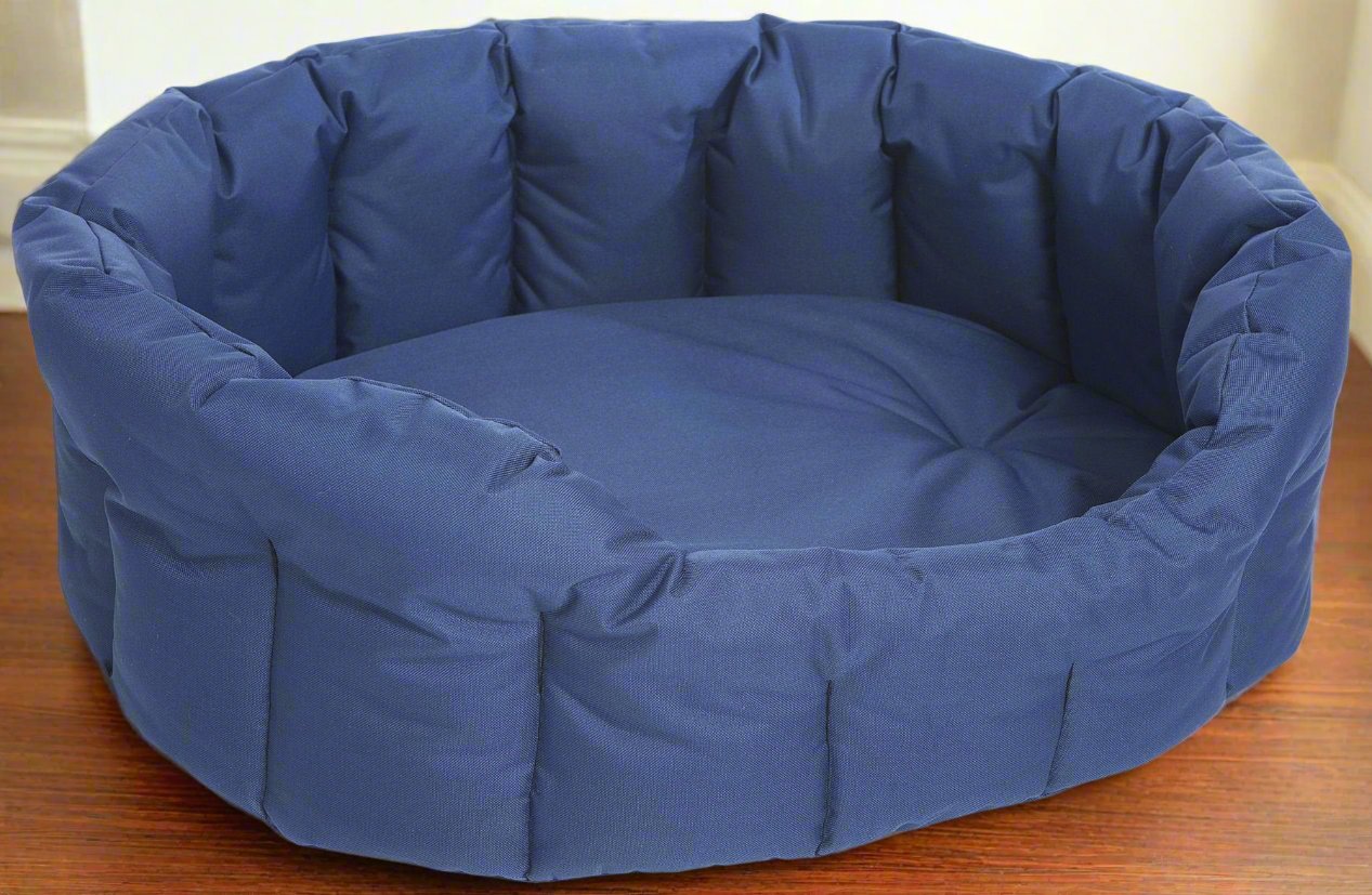 Navy blue oval dog bed with high padded sides and waterproof fabric, showing tufted cushioning on wooden floor