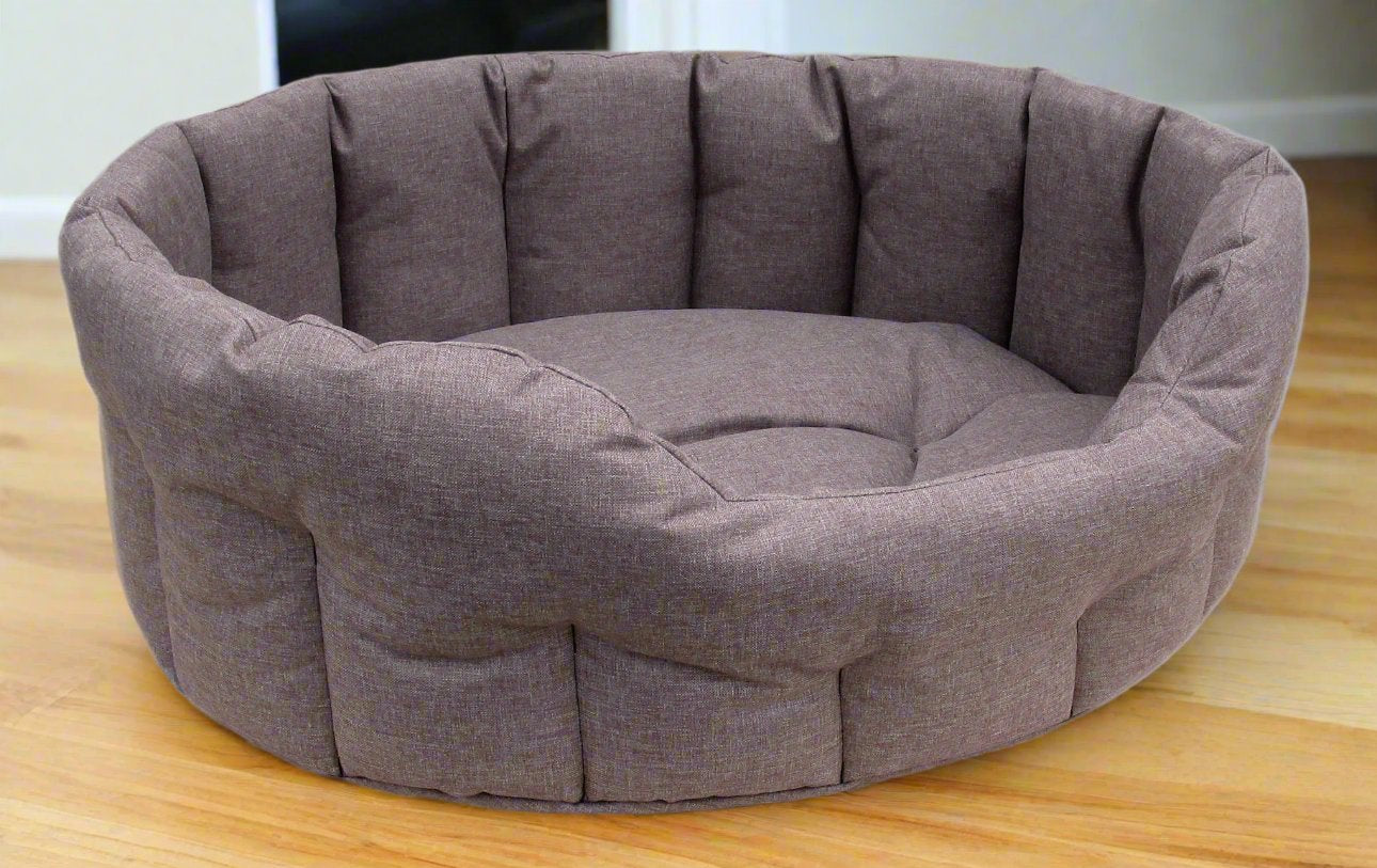 Grey waterproof oval dog bed with high quilted sides and plush cushioned interior on wooden floor