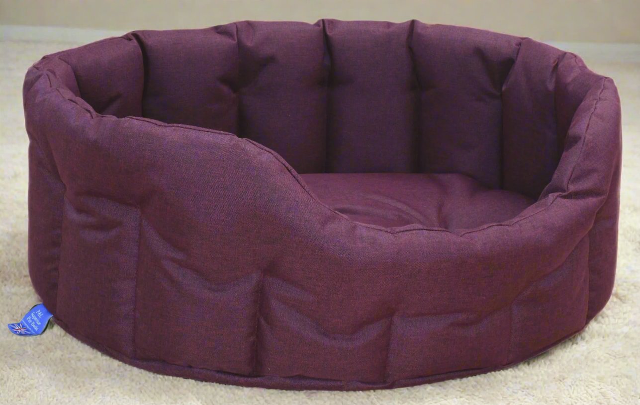 Purple waterproof oval dog bed with high quilted sides and durable fabric construction on cream carpet