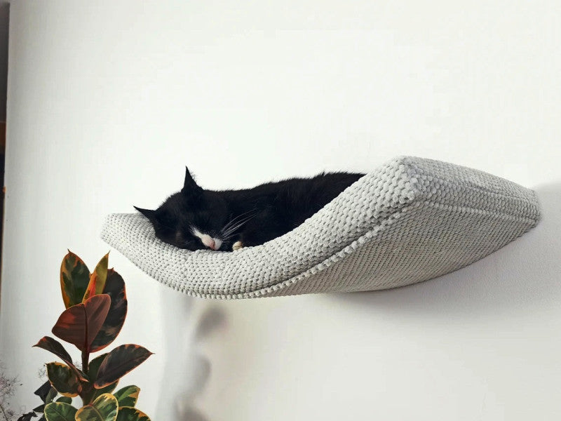 A black cat sleeping on a grey Cat's Atelier Floating Cat Wall Shelf