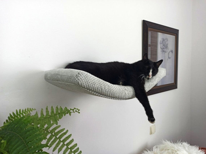 A black cat sleeping on a grey Cat's Atelier Floating Cat Wall Shelf