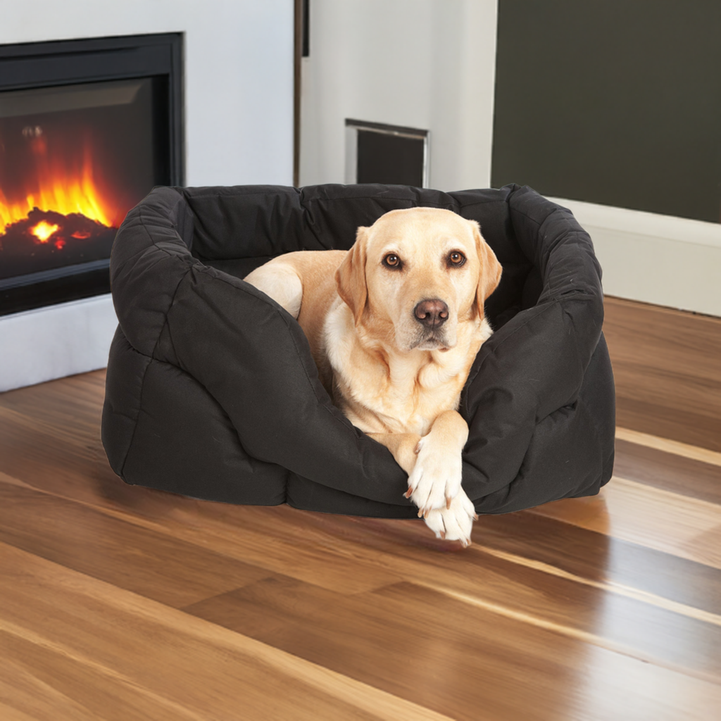Labrador dog relaxing in black waterproof rectangular dog bed by fireplace on wooden floor - heavy duty design