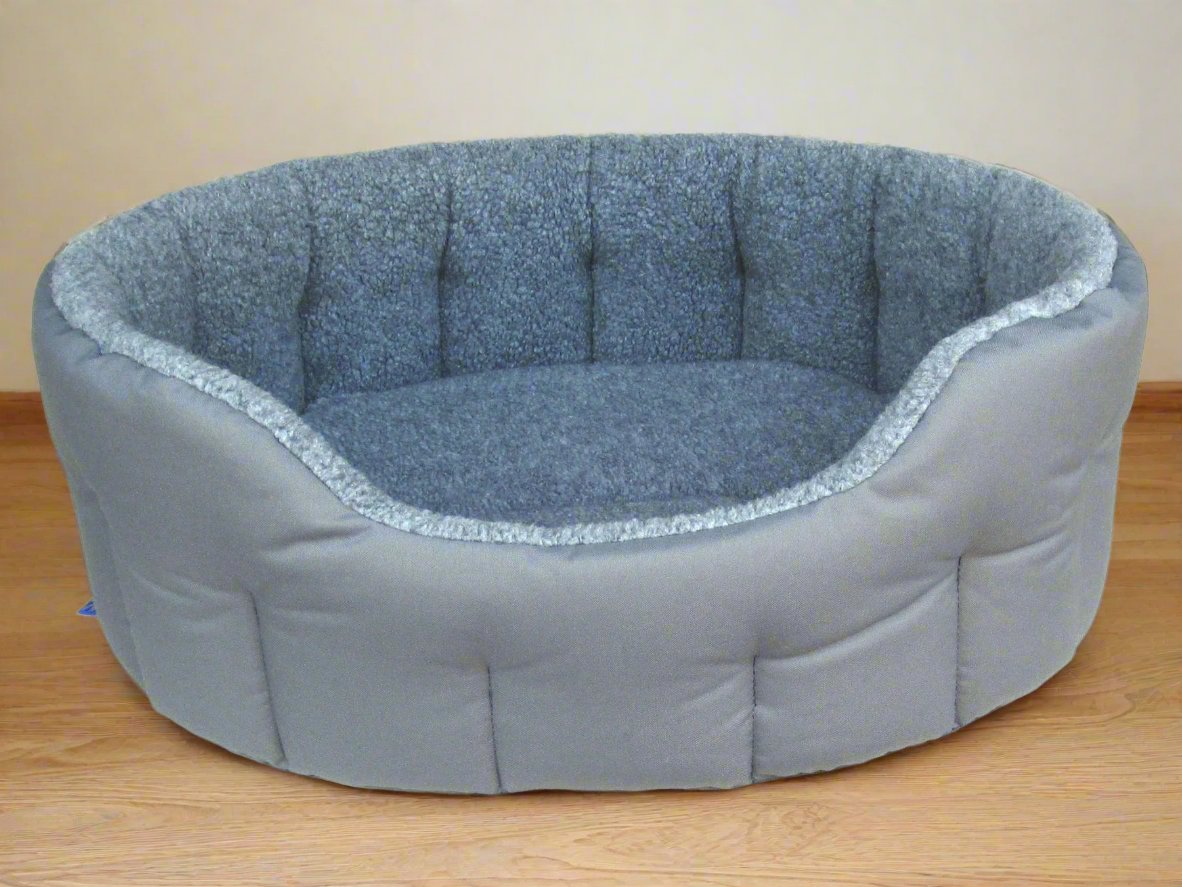 Grey oval dog bed with fleece lining and bolster sides, machine washable heavy duty design on wooden floor