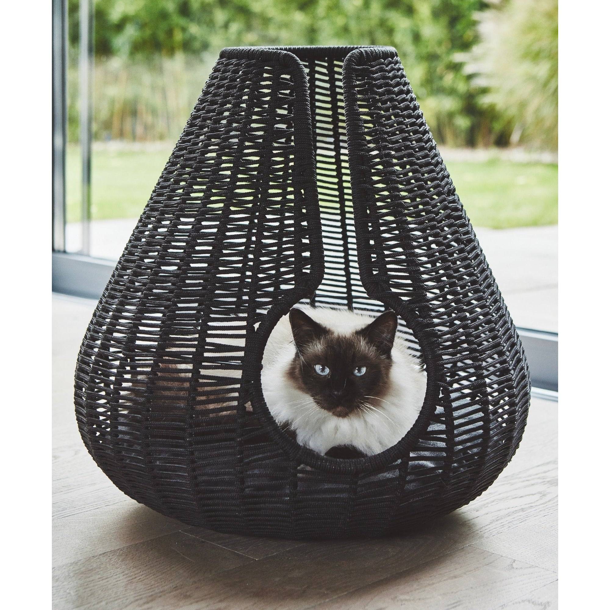 Siamese cat relaxing in MiaCara Perla woven cat cave, contemporary German design pet furniture for modern homes